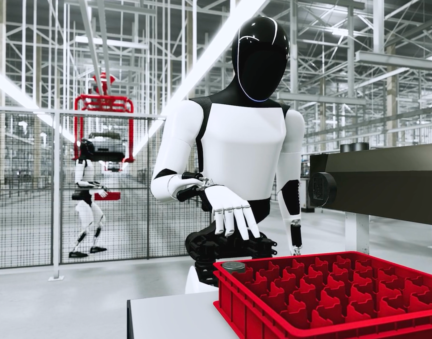 Humanoid robot handling a red crate at a workstation in a simulated factory